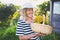 Happy smiling elderly senior woman in straw hat having fun posing in summer garden with flowers in basket. Farming, gardening,