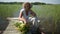 Happy smiling elderly senior woman in straw hat sitting on wooden pier by lake with flowers in basket. Farming