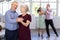 Happy smiling elderly woman enjoying impassioned merengue with male partner in latin dance salon. Social dancing concept