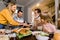 Happy smiling family, grandfather, parents and children sitting at festive table and eating tasty dinner. Mother puts