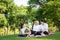 Happy smiling family sitting on mat in outdoor park,asian senior grandmother receiving massage by granddaughter,relax and have fun