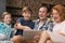 Happy Smiling Family Use Tablet Computer Sitting On Couch In Living Room, Parents Spending Time With Son And Daughter