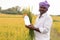 Happy smiling Farmer holding paddy crop and pesticide or Chemical fertilizer bottle in hand by looking camera near