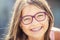 Happy smiling girl with dental braces and glasses. Young cute caucasian blond girl wearing teeth braces and glasses