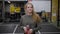 Happy smiling girl is walking across gymnastic hall before training, holding bottle with water