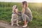 Happy smiling golden dog wearing a walking harness sitting facing its pretty young woman owne