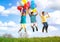 Happy smiling group of kids jumping with balloons on a green meadow