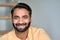 Happy smiling indian man looking at camera at home indoors. Close up portrait.