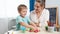 Happy smiling little boy playing with stamps and colorful clay with mother. Child using clay and playing dough