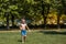 Happy smiling little boy run in water drops in the park, heat in the city