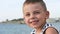 Happy smiling little boy in sailor stripes shirt on sky and sea background