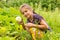 Happy smiling little girl harvesting fresh squashes in a garden and holding small fresh squash in her ha