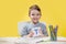 Happy smiling little preschool boy shows letters at home making homework at the morning before the school starts. English learning