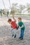 Happy smiling little preschool boys friends swinging on swings at playground outside on summer day. Happy childhood lifestyle