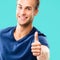 Happy smiling man in casual, showing thumb up gesture, aqua marine blue