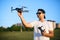 Happy smiling man holds small compact drone and remote controller in his hands. Pilot launches quadcopter from his palm