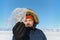 Happy smiling man wearing winter blue jacket and red hat holding piece of transparent crushed ice