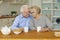 Happy smiling mature couple enjoying hot tea while spending time together at home