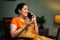 Happy smiling middle aged woman talking on mobile phone on chair at home - concept of excitement, good news and