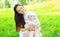 Happy smiling mother with baby on the grass in summer