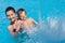 Happy smiling mother and child in goggles in swimming blue pool during summer vacation leisure