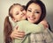 Happy smiling mother cuddling playful emotional kid girl in stud