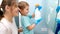 Happy smiling mother with little toddler son applying chemical detergent for washing and cleaning mirrors in bathroom