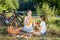 Happy smiling mother pouring drinks in paper cups on picnic at river