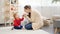 Happy smiling mother sitting on floor and playing with her little baby son. Baby development, family playing games, having fun