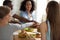 Happy smiling multiracial friends joining hands at meeting in cafe