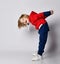 Happy smiling playful frolic blond kid boy in blue and red hoodie and pants bending over holding hands behind back