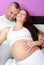 Happy smiling pregnant woman and her husband lying on bed