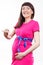 Happy smiling pregnant woman in pink dress with blue ribbon showing word february. Expecting for newborn and expansion of family