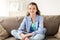 Happy smiling preteen girl sitting on sofa at home