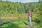 Happy smiling red-haired girl hiker with backpack and stick in the mountains near dead lake in the Carpathian mountains