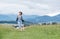 Happy smiling running beagle dog portrait with tongue out and owner female jogging by the mounting meadow grass path. Walking in n