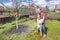 Happy and smiling siblings or sisters water the plants in the garden with hose