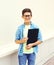 Happy smiling smart teenager boy in glasses with folder or book