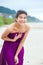 Happy, smiling teen girl in purple dress laughing on beach