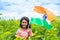 Happy smiling teenager girl holding indian flag at farmland - concept of freedom, patriotism and education