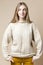 Happy Smiling Winsome Caucasian Blond Female Wearing Knitter Decorated Warm Sweater while Looking to Side Over Beige Background