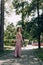 Happy and smiling woman with bouquet of flowers in a pink wedding dress and wedding ring. Running Bride, Bridesmaid. City park