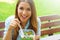 Happy smiling woman eating salad sitting in the park looks at camera with copy space area. Lunch salad take out container healthy