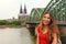 Happy smiling woman enjoying her travel in Germany. Beautiful traveler girl posing in front of the camera with Cologne Cathedral