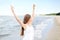 Happy smiling woman in free happiness bliss on ocean beach standing with raising hands. Portrait of a multicultural