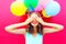 Happy smiling woman is hides her eyes with hands having fun over an air colorful balloons pink