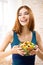 Happy smiling woman holding greece salad with cheese, indoor. Beautiful girl - keto dieting, weight loss, healthy eating