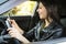 Happy smiling woman holding her smart phone sitting inside a car. Female driver laughing reading message and chatting in