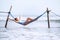 Happy smiling woman lies in hammock swing over the ocean surf li