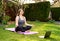 Happy smiling woman practicing yoga meditating online in garden outdoors during quarantine.